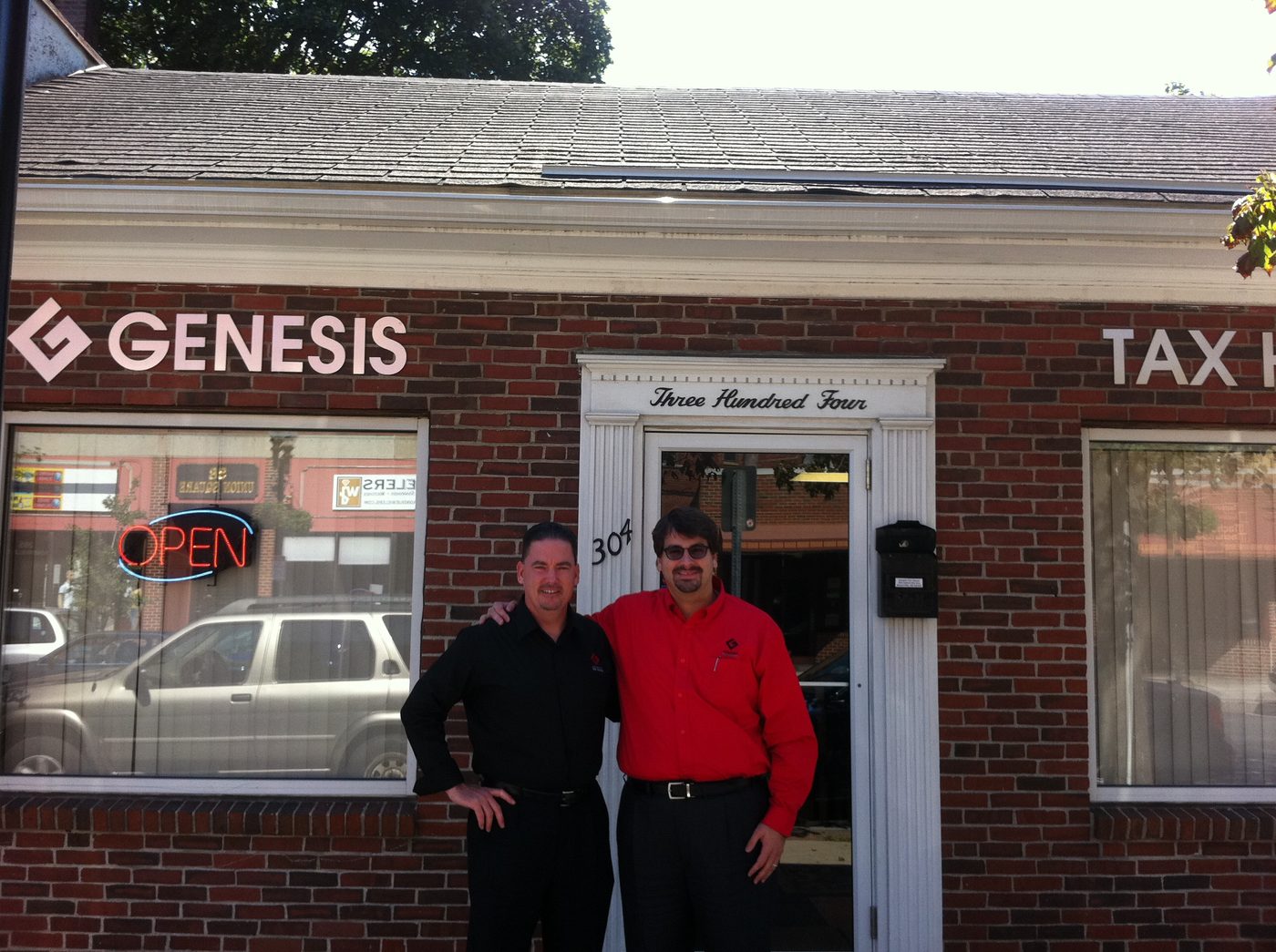 Igor Gomes and Brian Downey in front of an earlier Genesis Tax House office in Somerville, a brick building with the Genesis sign